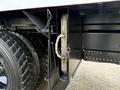 A 2015 Freightliner M2 with a visible storage compartment containing metal plates secured with a chain and a rope