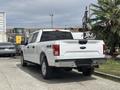 A white 2017 Ford F-150 pickup truck parked, showcasing its rear design and 4x4 badge on the tailgate