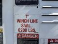 A warning label attached to equipment stating 1 inch winch line S.W.L. 6200 lbs and includes a caution about the dangers of the device