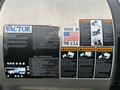 A close-up of a metal panel displaying various labels and service checklists for a 2014 International 7500 truck with warning symbols and a made in the USA tag