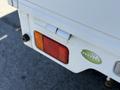 A 2009 Suzuki Carry with a rear light cluster featuring red and amber lenses and a small green sticker on the body