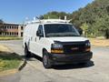 A 2019 GMC Savana cargo van in white with a black front bumper and silver wheels featuring a roof rack