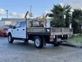 A white 2020 Ford F-350 with a flatbed and tool rack visible from the rear angle