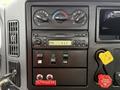The dashboard of a 2006 International 4300 featuring climate controls a radio and various operational switches including a power button and an outrigger control