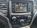 The dashboard of a 2015 Jeep Grand Cherokee featuring a touchscreen display with radio settings and control knobs for climate and audio settings