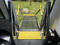 A yellow and gray wheelchair ramp is extended from the back of a 2013 Chevrolet Express van with mesh flooring and safety straps attached to the sides