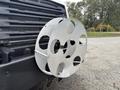 A silver metal circular grill guard with multiple holes attached to the front of a 2013 Freightliner 114SD truck