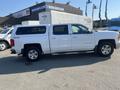 A white 2015 Chevrolet Silverado 1500 with a cap on the truck bed parked on a lot