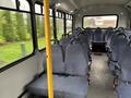 Interior of a 2018 Chevrolet Express passenger van featuring rows of blue fabric seats with seatbelts and a yellow pole for support