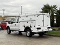 A 2015 Ford F-350 SD truck with a white utility body featuring multiple compartments and a flatbed design