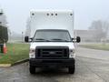 A white 2019 Ford Econoline van with a large boxy cargo area in the rear parked on a driveway facing forward with a visible front grille and headlights
