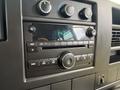 Dashboard of a 2013 Chevrolet Express featuring a radio with knobs buttons and a digital clock displaying the time