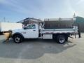 A white 2016 RAM 5500 dump truck with a plow attached and an open dump bed positioned on the passenger side