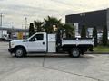 A 2015 Ford F-350 flatbed truck with a white cab and a silver service body parked on a driveway