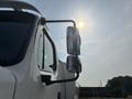 A 2010 Freightliner M2 106 with a shiny side mirror prominently displayed in the foreground and the sun reflecting off it