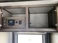 A wooden cabinet with two open compartments featuring a control panel and various electrical outlets inside