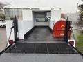 A 2000 Ford F-450 flatbed truck with a metal mesh floor and a red tank mounted on the side
