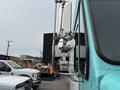A 2020 Freightliner MT45 with a side mirror reflecting its surroundings and a bright turquoise color on the driver's side