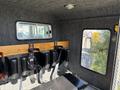 Interior of a 1994 Volvo FE 42 with padded seats and safety belts mounted along a wooden panel on one side