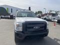A 2014 Ford F-250 Super Duty truck facing the camera with a white exterior and a prominent black front grille featuring the Ford logo
