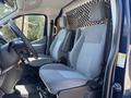 The interior of a 2016 Ford Transit 150 featuring two gray cloth seats with armrests and a steering wheel in the foreground