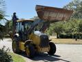 A yellow 2013 John Deere 710K backhoe loader with an elevated front bucket and a rear digging arm