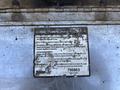 A weathered maintenance and safety instruction label attached to a metallic surface displaying text and a serial number