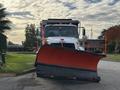 A white 2013 Freightliner 114SD snow plow truck with an orange plow blade attached at the front