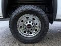 Close-up of the wheel and tire of a 2017 GMC Sierra 3500HD featuring a shiny chrome rim and rugged all-terrain tire