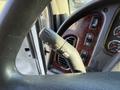 Close-up of the steering wheel and dashboard controls of a 2012 Freightliner M2 106 showing various knobs and buttons for vehicle functions