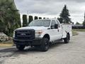 A white 2013 Ford F-250 Super Duty truck with a black grille and off-road tires, featuring a utility bed for equipment storage