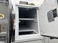 A silver storage compartment of a 2014 Ford F-550 with shelves inside and a hook exposed