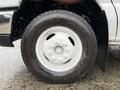 A close-up of a white tire on a 2015 Ford Econoline featuring a six-bolt pattern and a smooth tread design
