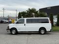 A white 2004 Chevrolet Express van parked with sliding side doors and chrome wheels