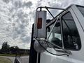 A 1998 Freightliner FL80 truck with a prominent side view mirror and a mounted amber light on the cab