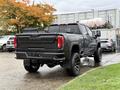 A black 2022 GMC Sierra 3500HD with large wheels and a lifted stance is shown from the rear angle, highlighting its bold design and distinctive rear lights