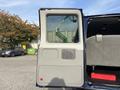 A 2013 Ford E-350 Super Duty van with the sliding side door open revealing a gray interior and a window with a view outside
