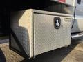 A diamond plate storage box installed on the side of a 2006 Ford F-550 truck with a padlock on the front