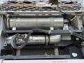 A 2012 Global M4 engine compartment featuring metal exhaust components and associated piping with visible labels and a clean radiator sign