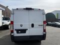 A 2017 RAM Promaster van viewed from the rear with a plain white surface and a logo in the center above the rear doors