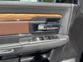 The interior door panel of a 2015 RAM 1500 featuring wood and leather accents with window controls and a door handle