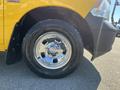 Close-up of a chrome wheel on a yellow 2015 RAM 1500 showcasing its tire tread and shiny rim details
