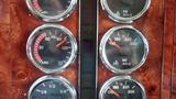 A panel of gauges from a 2003 International 5600i showing air pressure and temperature levels with analog dials and a wood finish