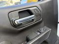 Interior door panel of a 2024 Chevrolet Silverado 1500 featuring a metallic handle and control buttons for windows and locks