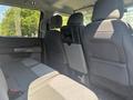 Interior view of the backseat of a 2023 Ford F-350 SD featuring gray cloth upholstery and a fold-down armrest with cupholders