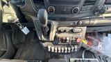 Interior view of a 2021 Ford Transit showing the gear shift, control panel with various buttons and switches, and a key in the ignition