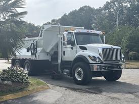 A 2013 International WorkStar truck with a large dump bed is parked. The truck has a white and black color scheme and is equipped with orange lights on the roof