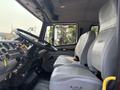 Interior view of a 1999 Freightliner FL80 showing the driver's seat and passenger seat with a steering wheel and dashboard controls visible