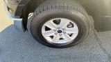 A close-up of a silver alloy wheel with a large black tire featuring treads and the Ford logo on a 2016 Ford F-150