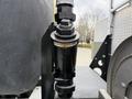 A black strainer connected to the side of a vehicle with a label reading STRAINER CHECK DAILY